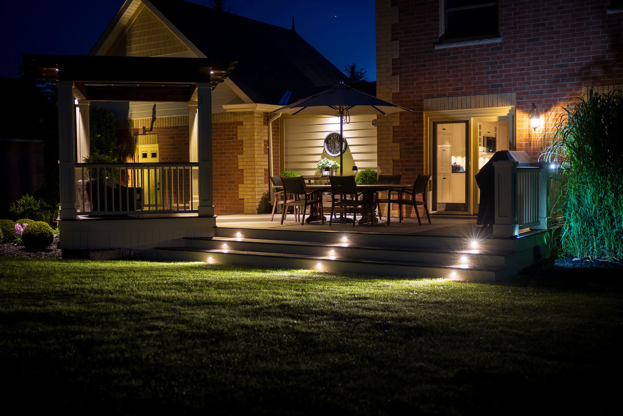 Deck with lit steps, covered porch and patio umbrella at night, deck building in Wheaton